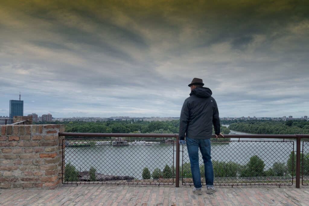 A man stands at Belgrade fort and looks at the city below