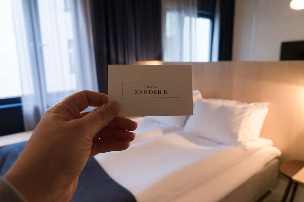 Hand holding Zander K business card in a hotel room