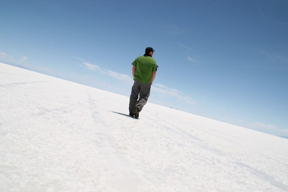 A man walking away from the camera on the Bolivian salt flats on a clear day