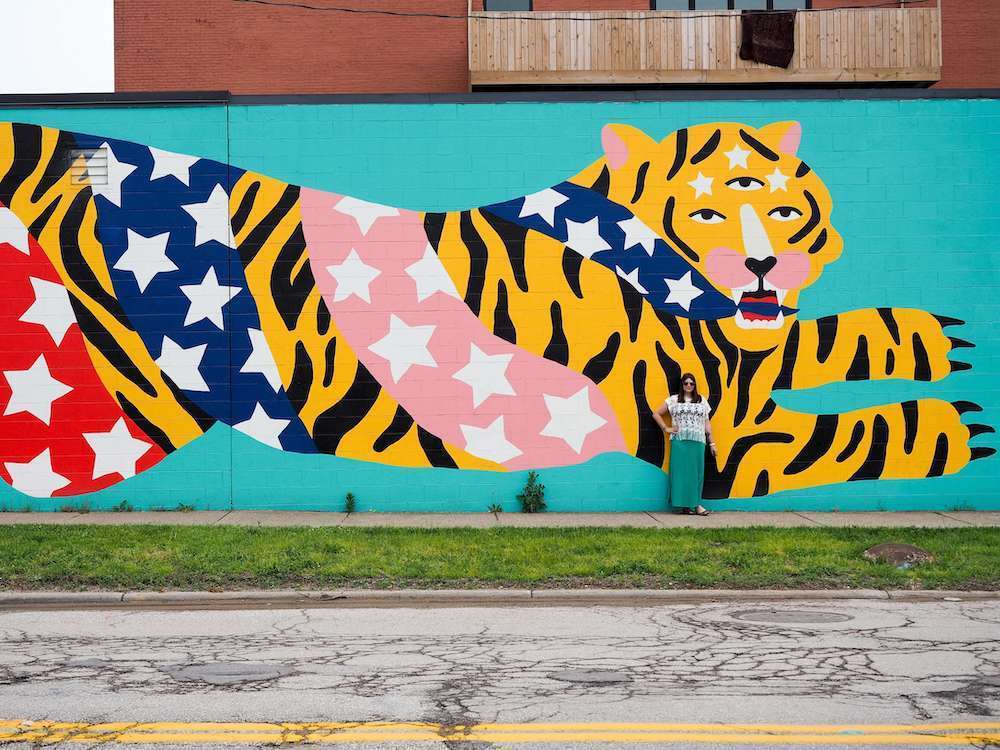 A woman stands in front of a tiger street art mural in Cleveland Ohio