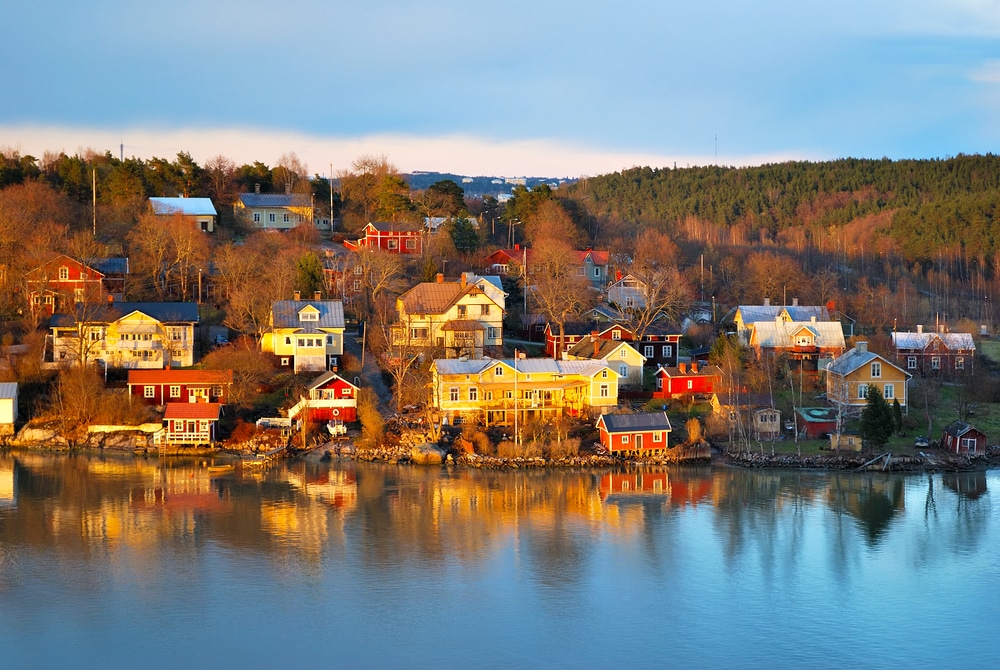 Beautiful wooden colorful houses near water in Finland at sunset