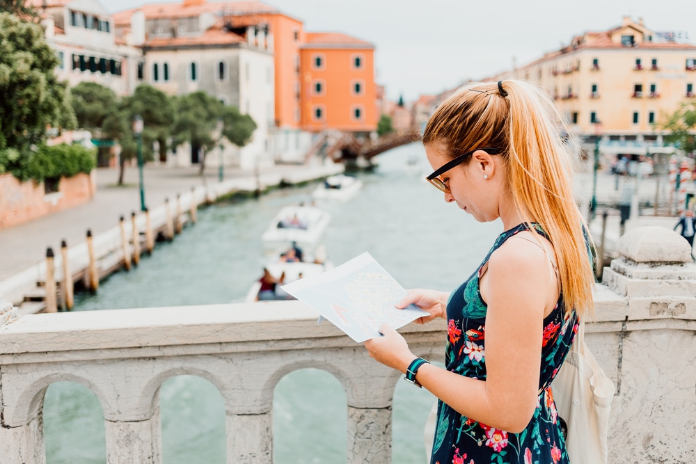 woman looking at a map on bridge in Venice