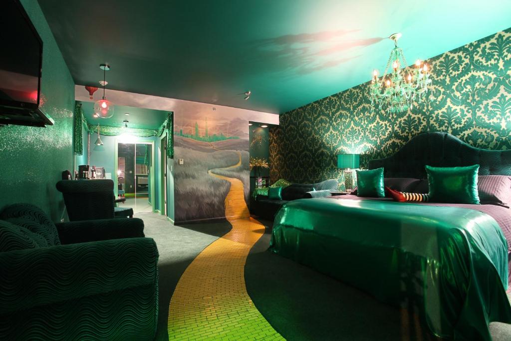 interior of Wizard of Oz room at Roxbury Hotel, very green with gold accents, wicked witch feet on bed, mural of yellow brick road on floor and wall