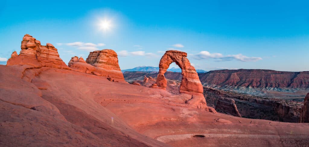 Classic view of famous Delicate Arch, symbol of Utah and a popular scenic tourist attraction, illuminated  by full moon at night in summer, Arches National Park, Moab, Utah, USA