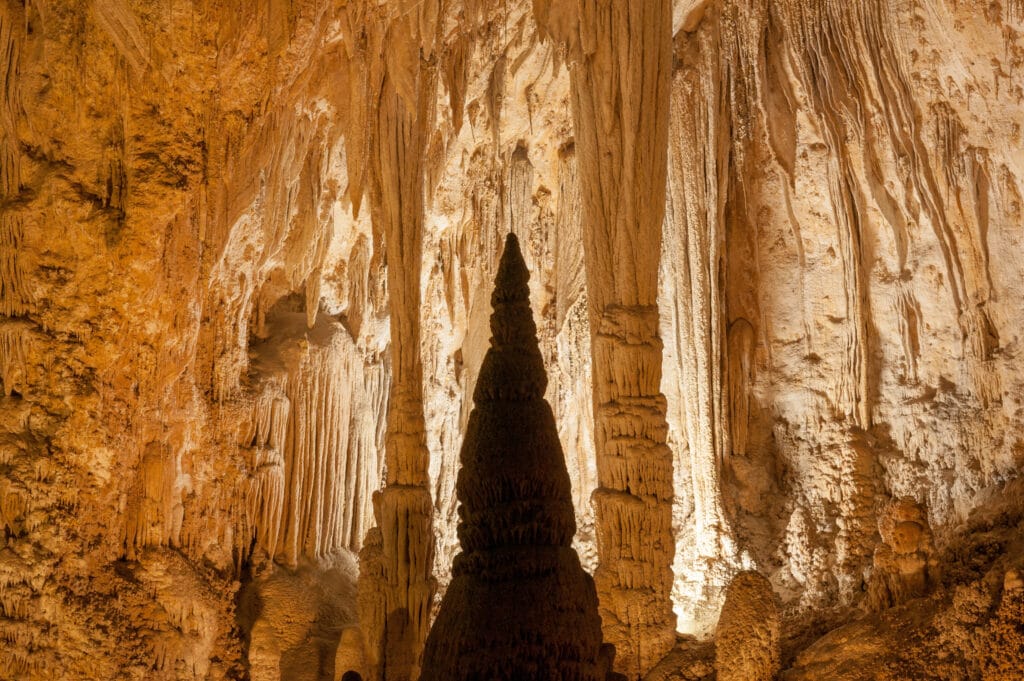 illuminated inside of cave with lots of stalactites and stalagmites
