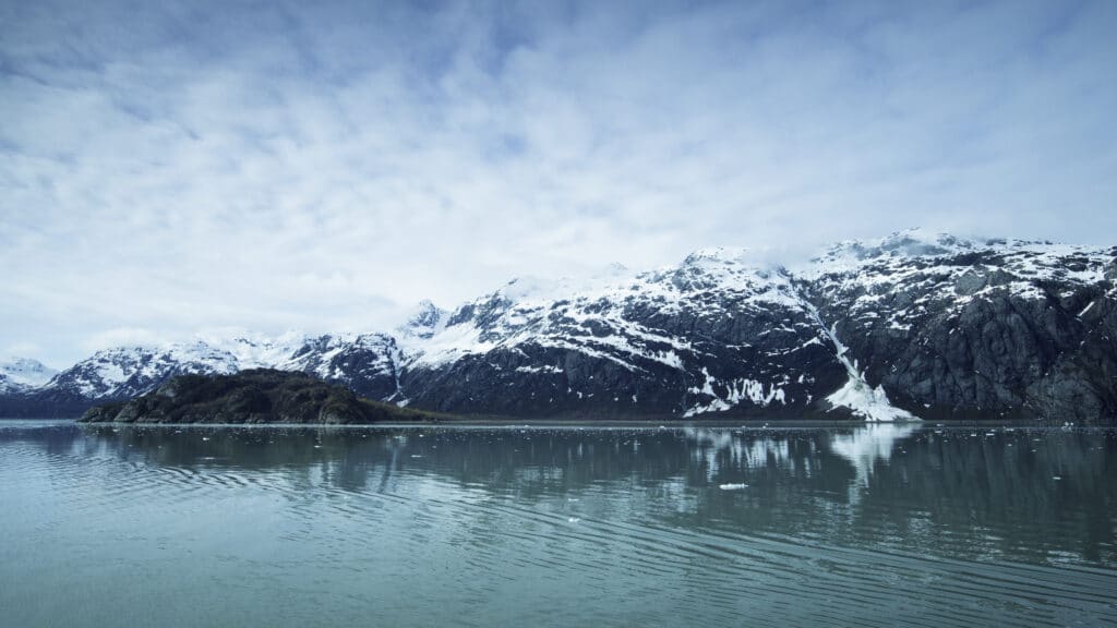 view of lake in front of snowy mountains in glacier bay national park