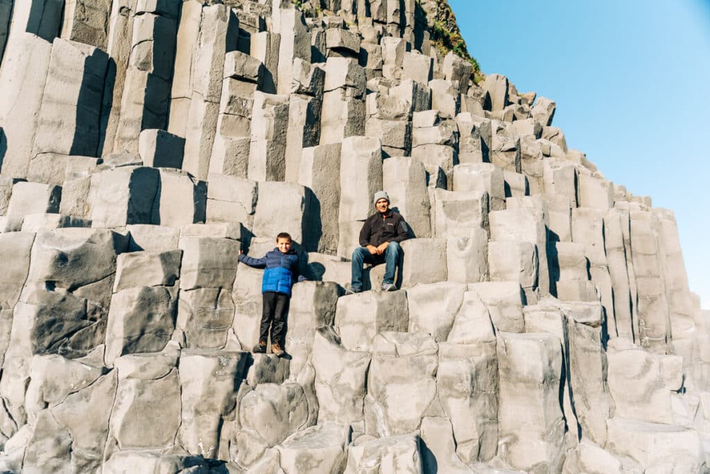 My family sitting on the basalt columns Reynisfjara Black Sand Beach in Iceland