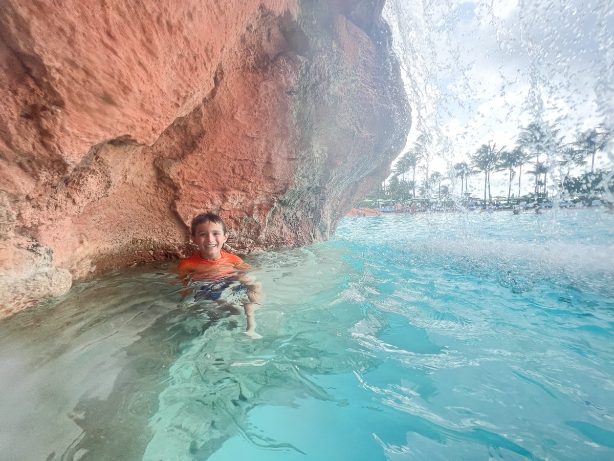 My son under a waterfall in the pool at Atlantis