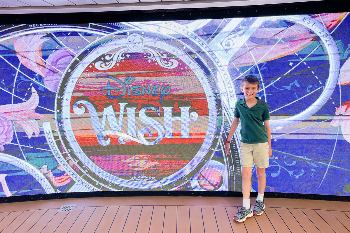my son in front of the Disney Wish sign