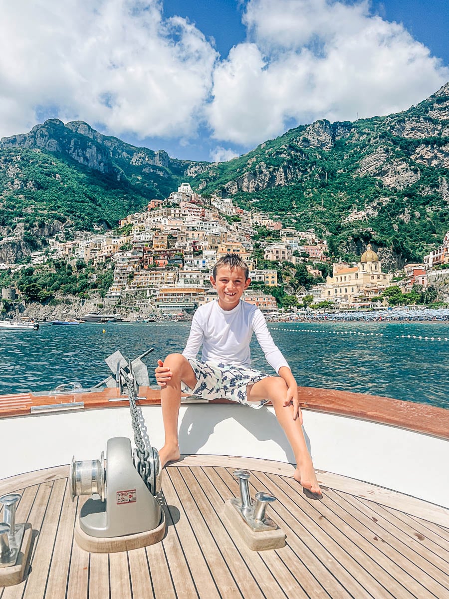 my son on a boat with Positano in the background
