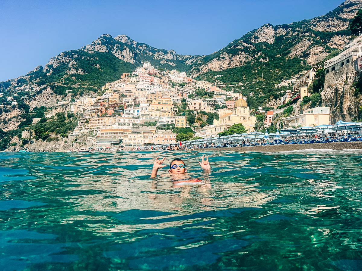 my son in the water with positano in the background