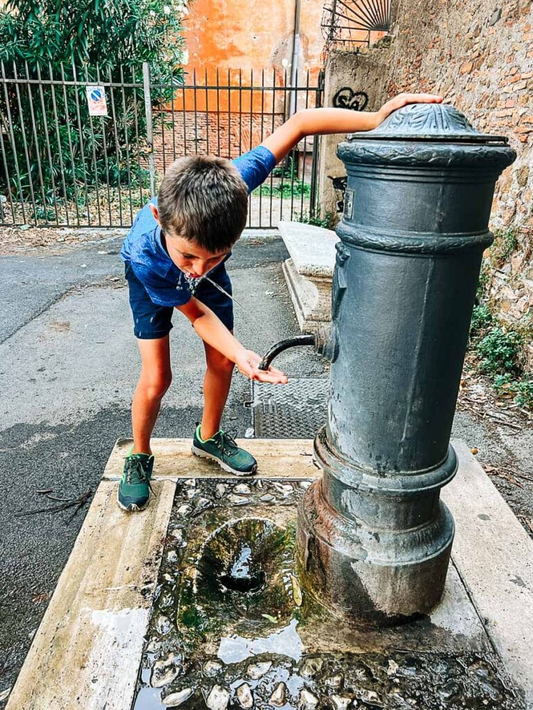 my son drinking from an antique fountain in Rome