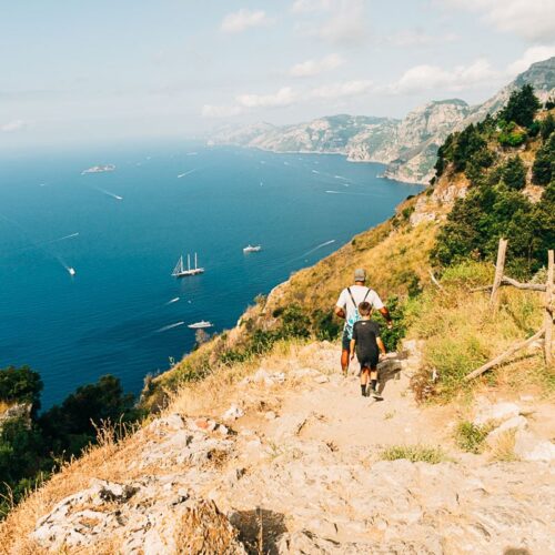 my son and husband hiking path of the gods with the sea behind them