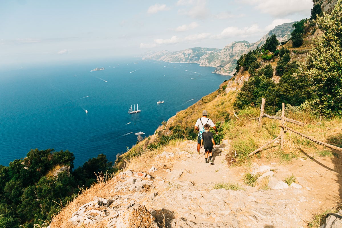 my son and husband hiking path of the gods with the sea behind them